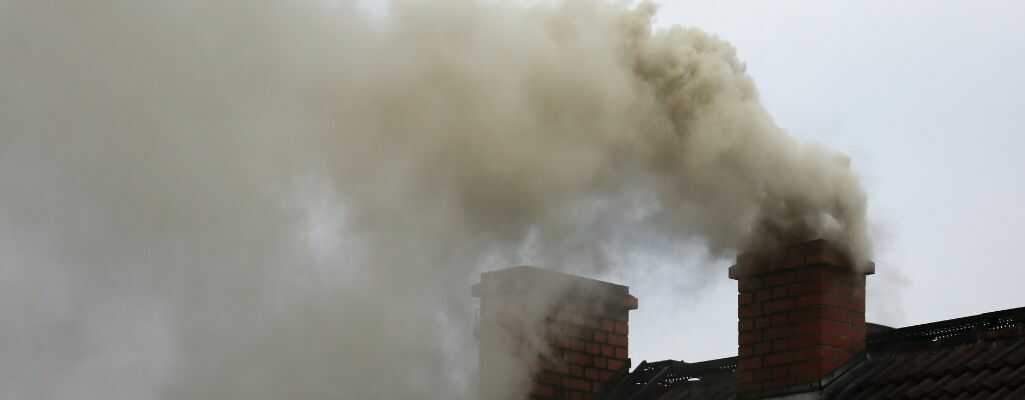 Dymiące kominy w mieście wydzielające zanieczyszczenia powietrza szkodliwe dla zdrowia.